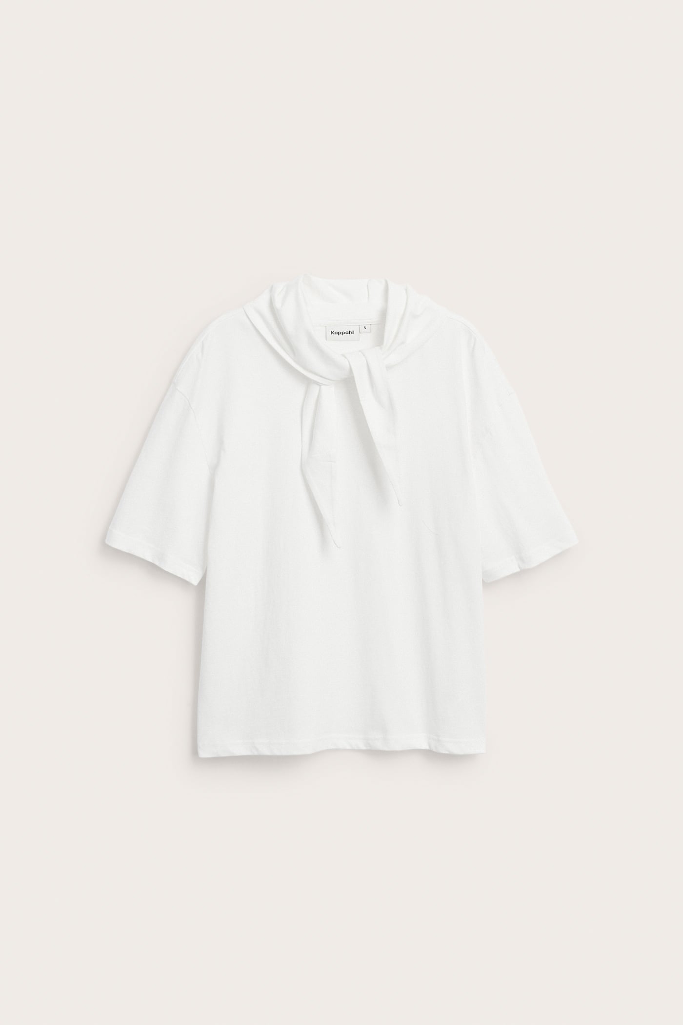 Frontvy av en offwhite kortärmad bomulls-t-shirt med en fastsatt sjaldetalj knuten vid halsen.