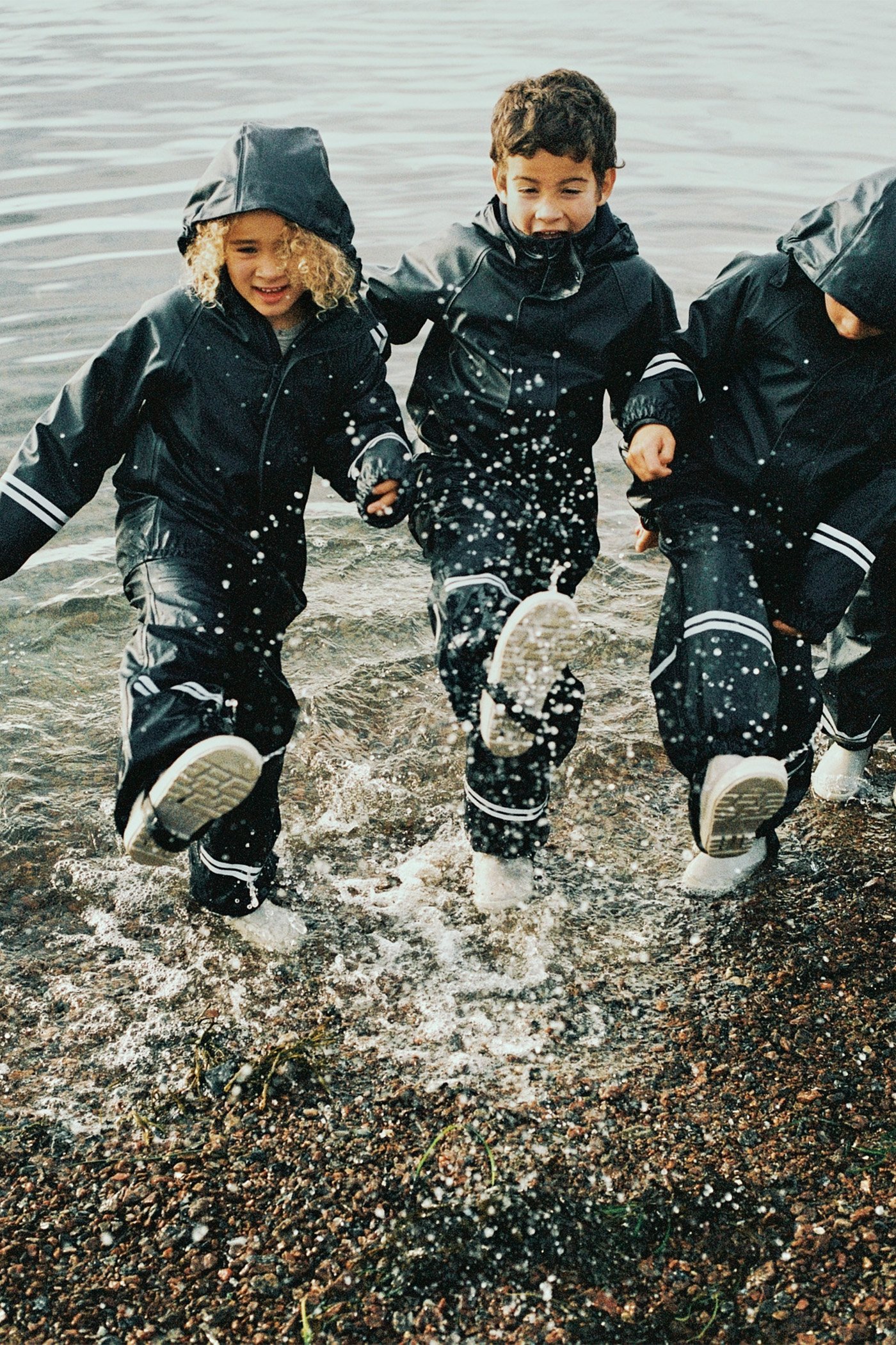 Dzieci nad morzem w podszewkach przeciwdeszczowych.