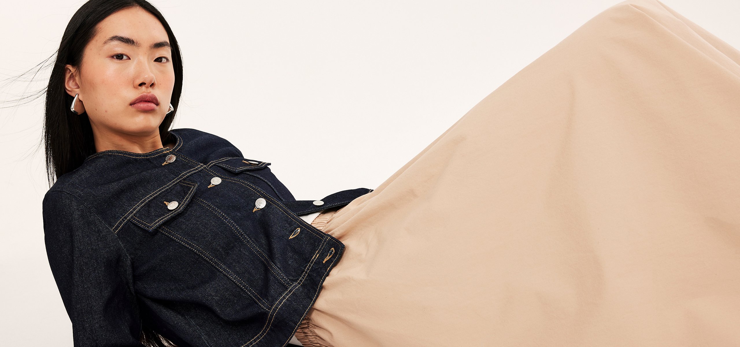 Kvinna i jeansjacka och beige kjol
