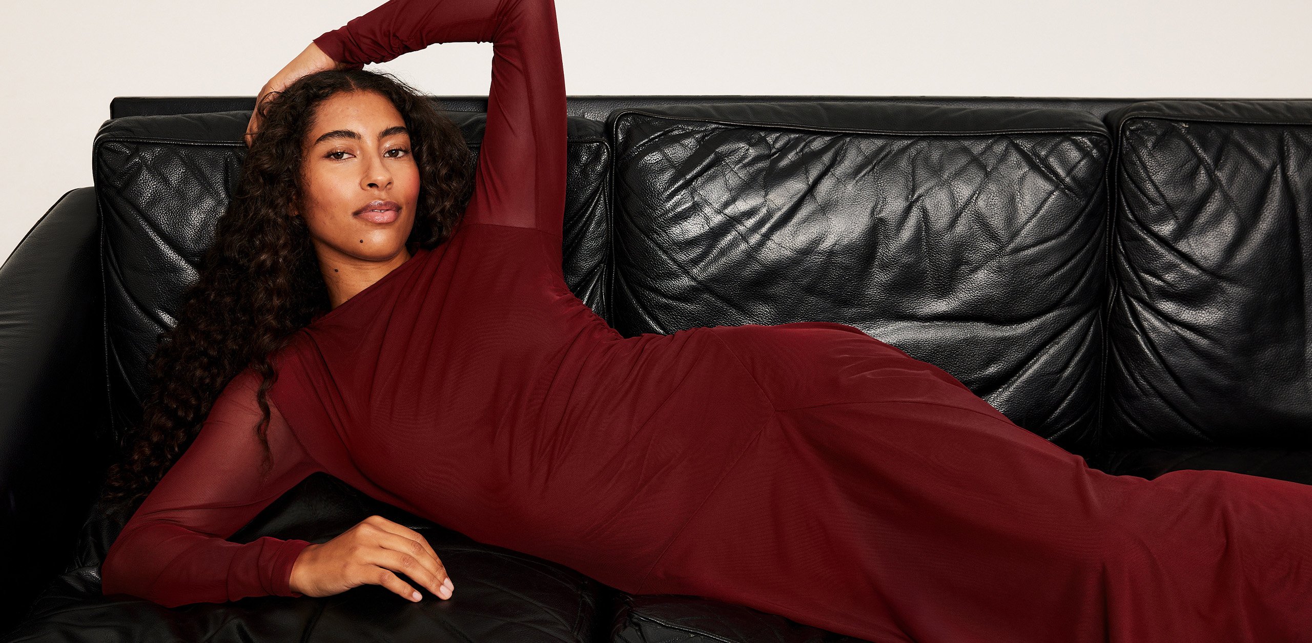 Nainen viininpunaisessa vartalonmyötäisessä mekossa, joka on valmistettu verkkokankaasta