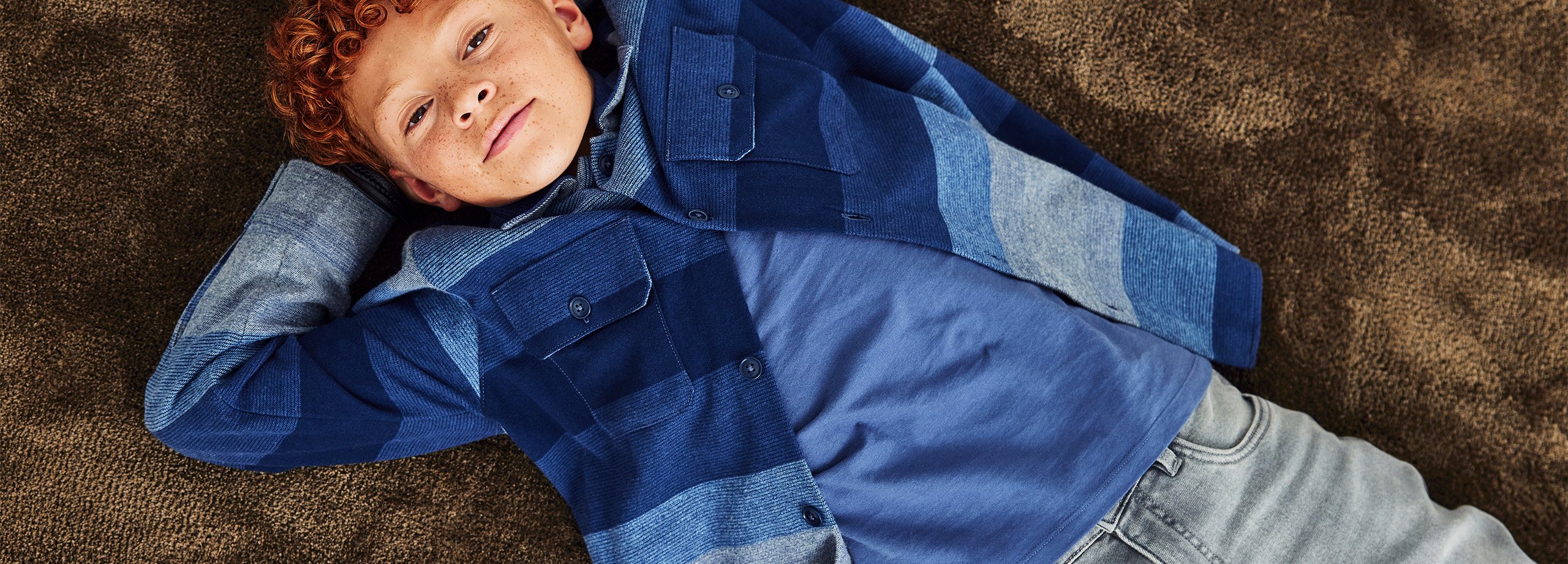 Mies sinisessä, raidallinen päällyspaita ja harmaat farkut.