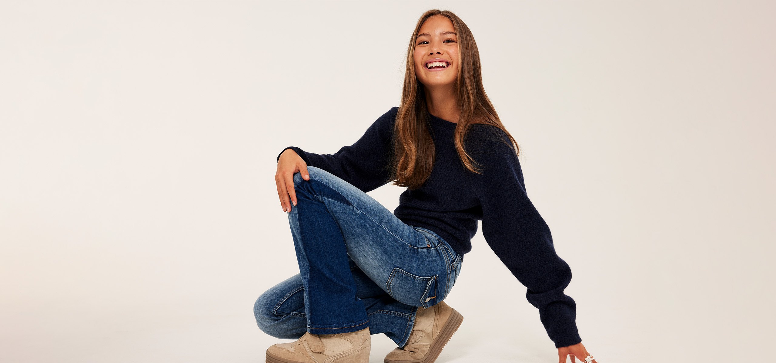 Dziewczyna w dwukolorowych dżinsach z bootcutem i dzierganym swetrze.