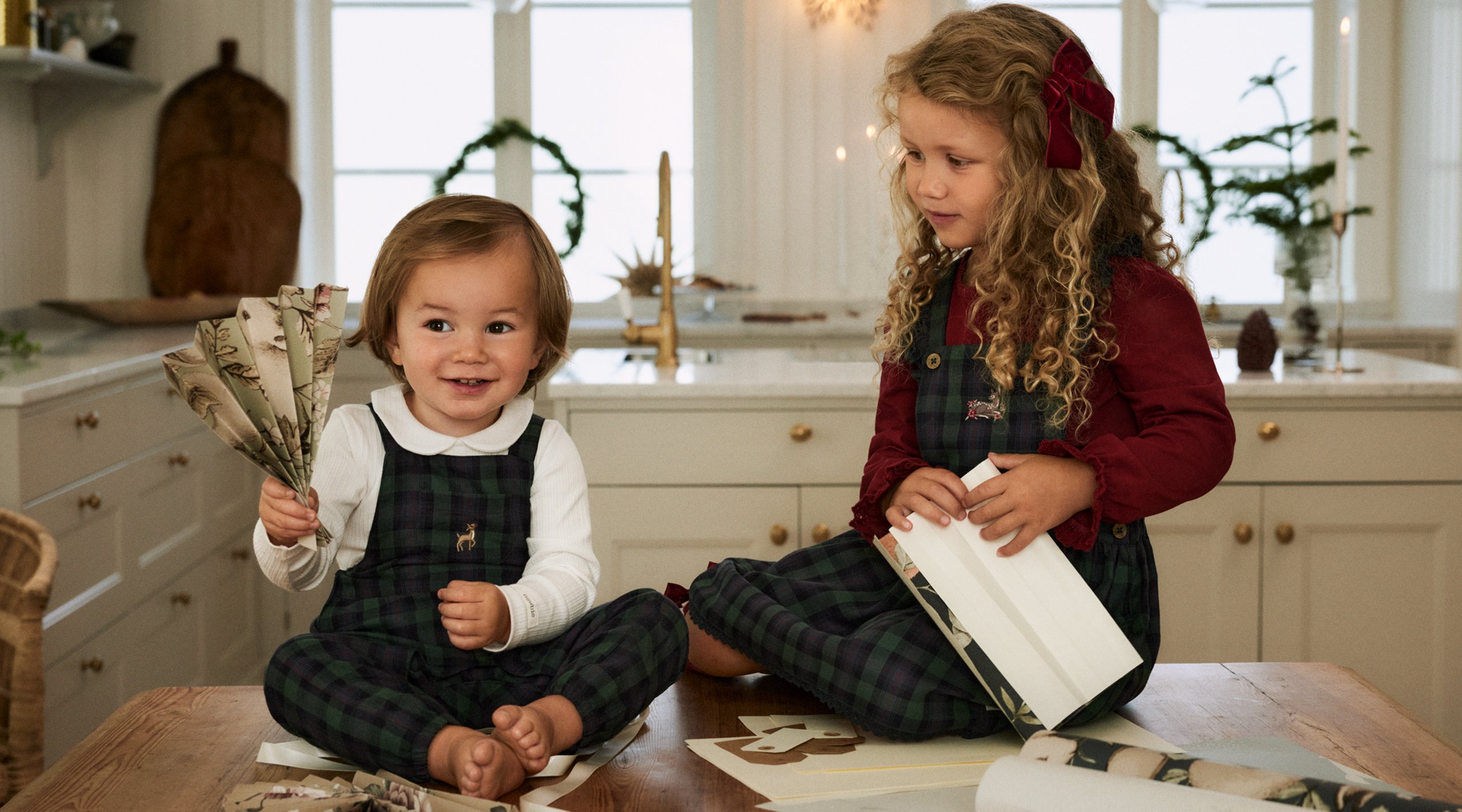 Tyttö ja poika leikkivät keittiössä pukeutuneina Newbie-lehden jouluvaatteisiin.