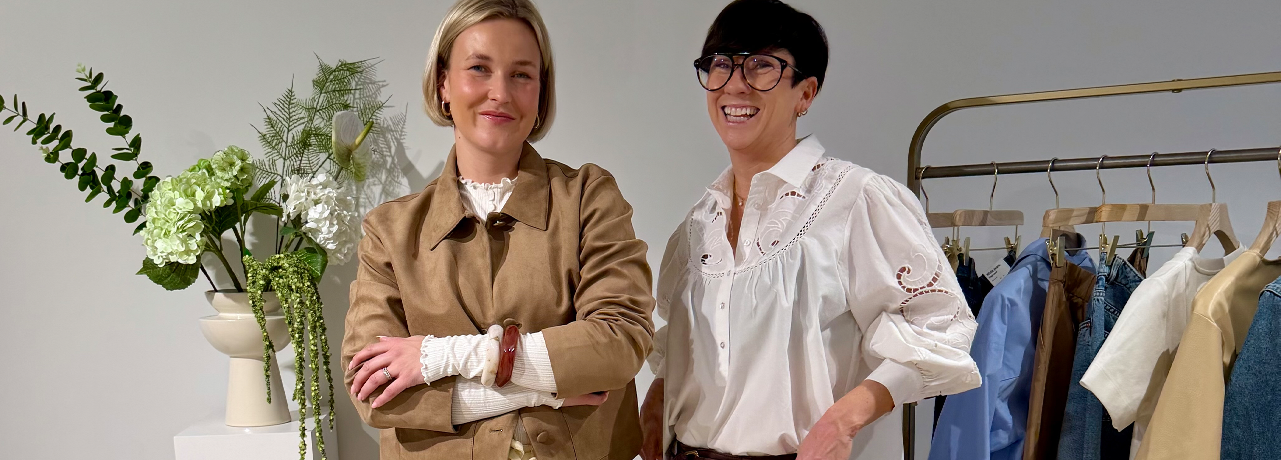 To kvinner i vårklær og et klesstativ.