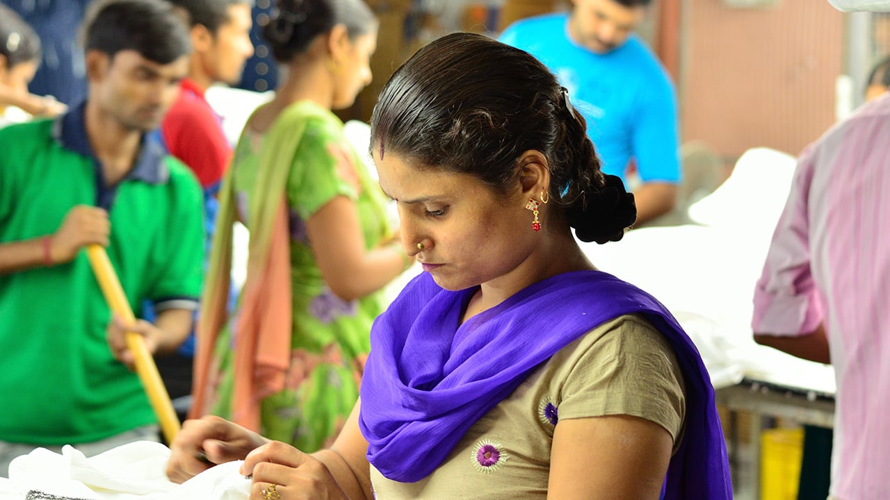 Women and men in colorful clothing working with textiles.