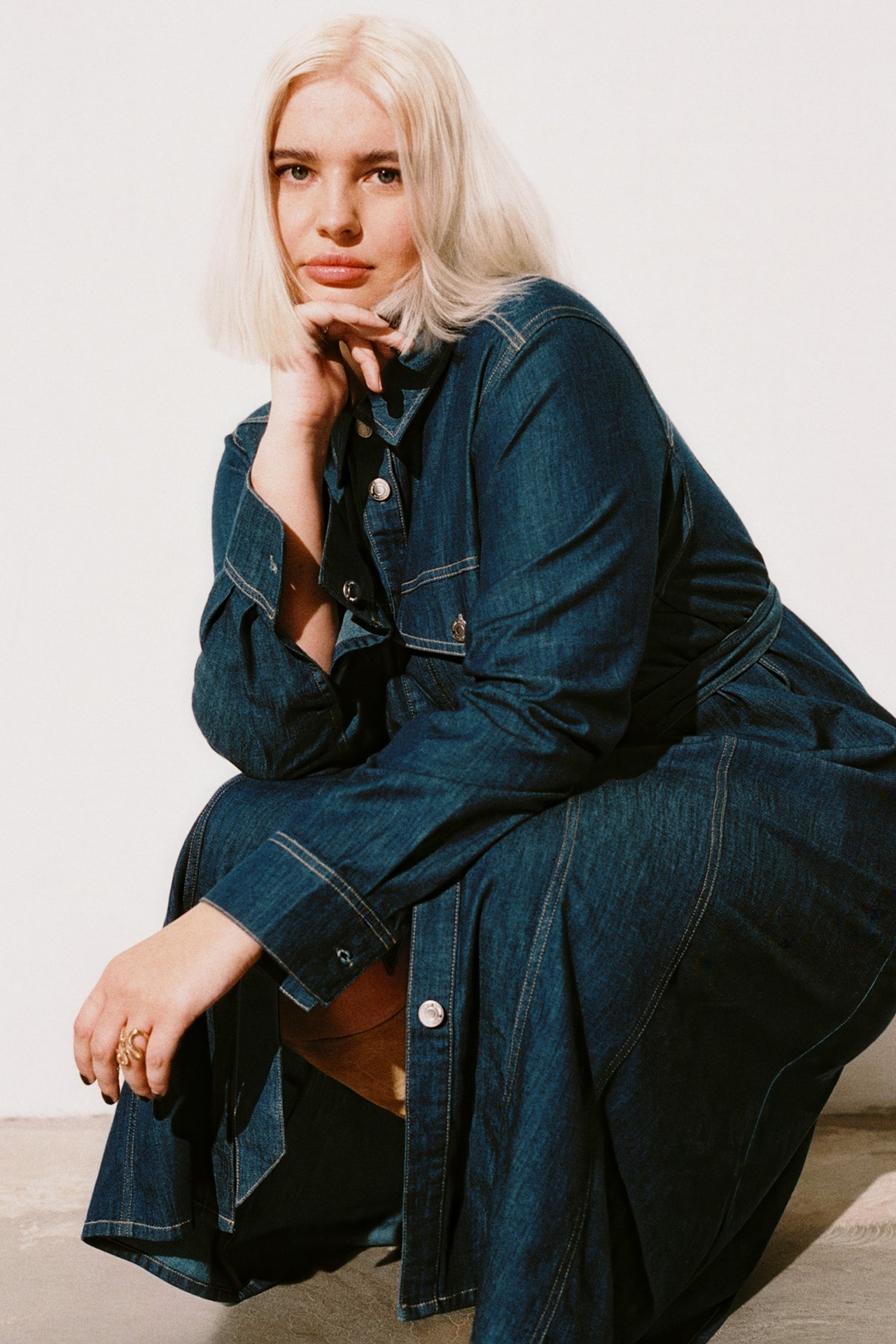 Kvinna med större storlek i lång jeansklänning.