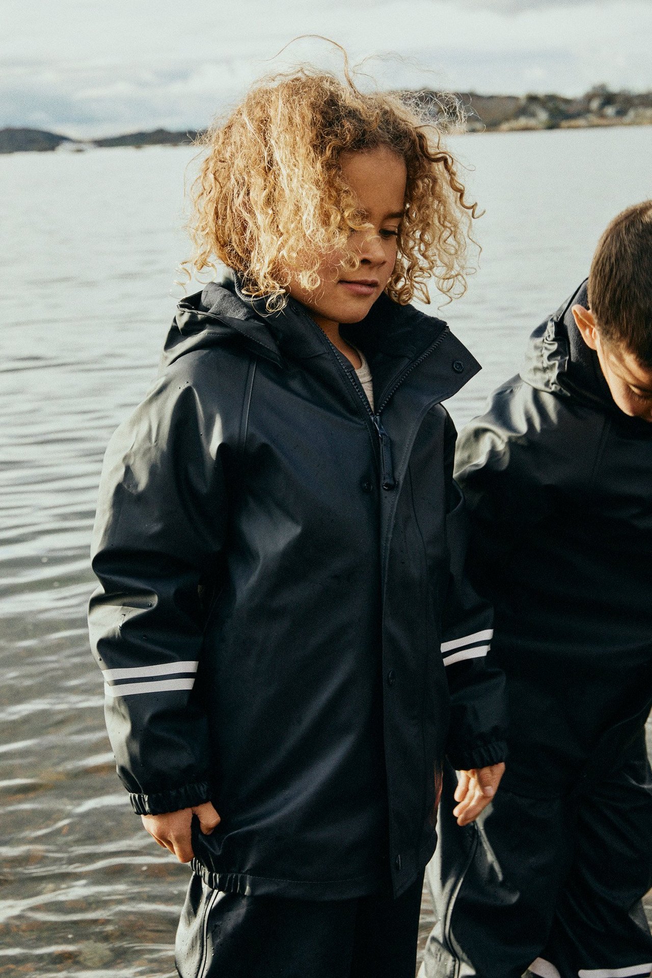 Dzieci nad morzem w podszewkach przeciwdeszczowych.