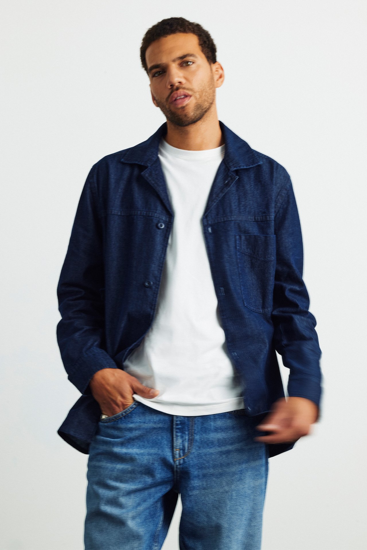 Mężczyzna ubrany w dżinsy, biały t-shirt i dżinsową koszulkę.