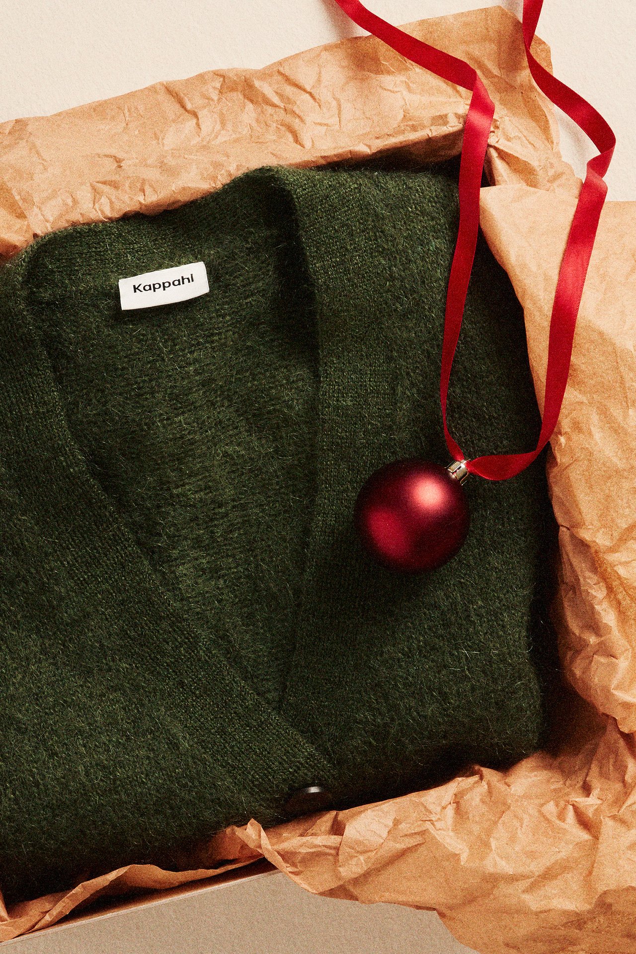 Zielony sweter z dzianiny w otwartym opakowaniu.