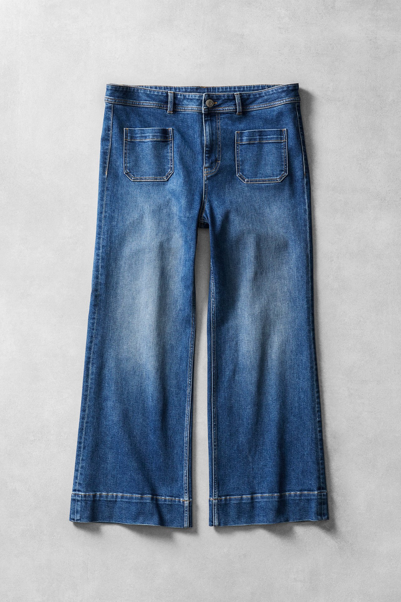 Nainen sinisissä bootcut-farkuissa ja valkoisessa paidassa