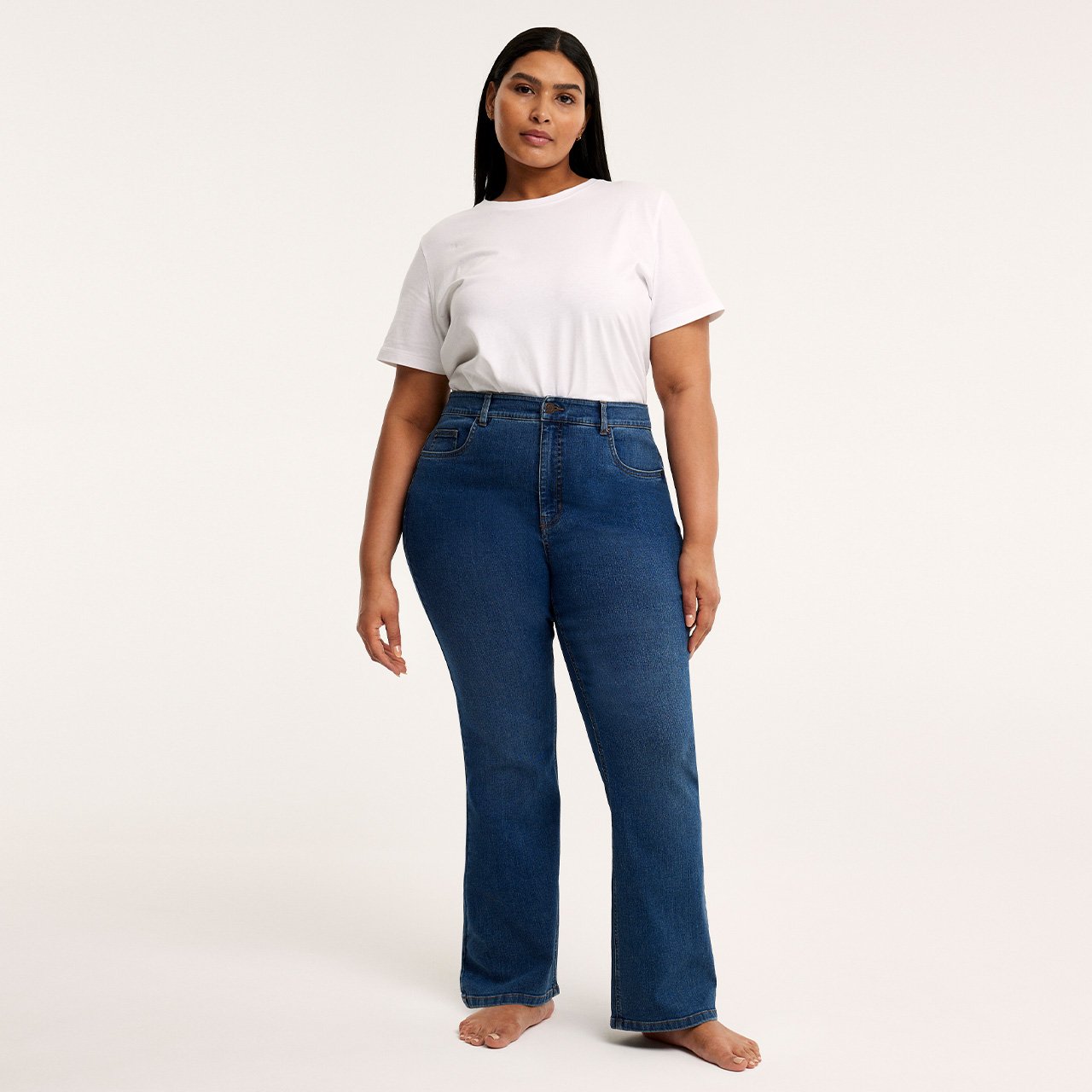 Kvinna i blåa bootcut jeans och vit t-shirt