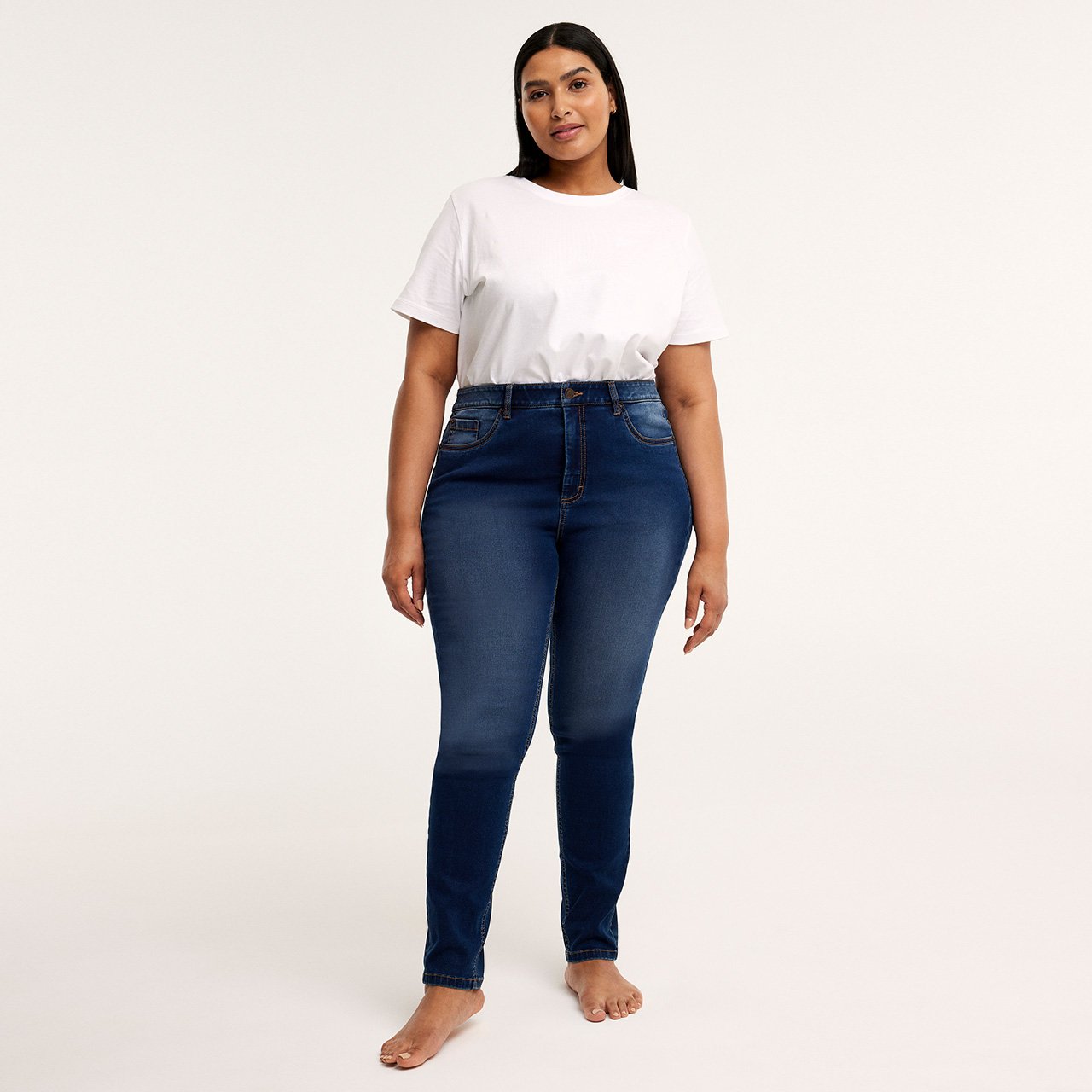 Kvinna med vit topp och blåa slim jeans