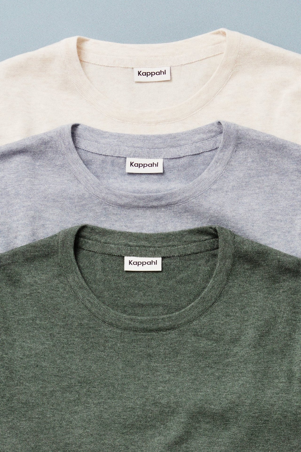 Kolme neulottua miesten villapaitaa valokuvattu sinistä taustaa vasten