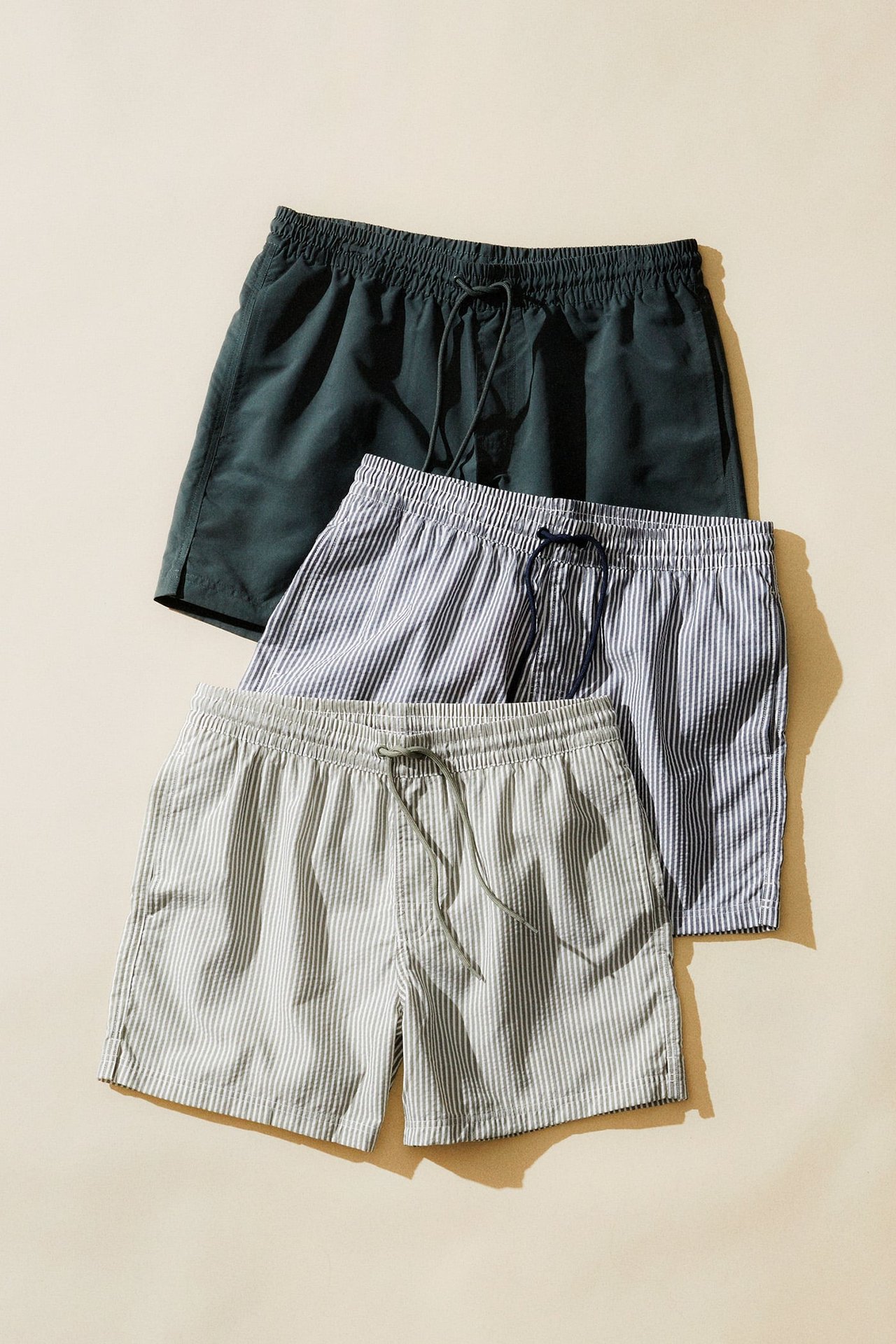 Badshorts till män. Tre badshorts liggandes intill varandra. 
