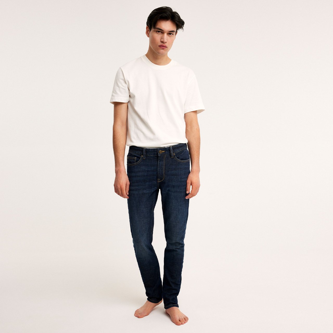 Mann i hvit t-skjorte, blå slanke jeans