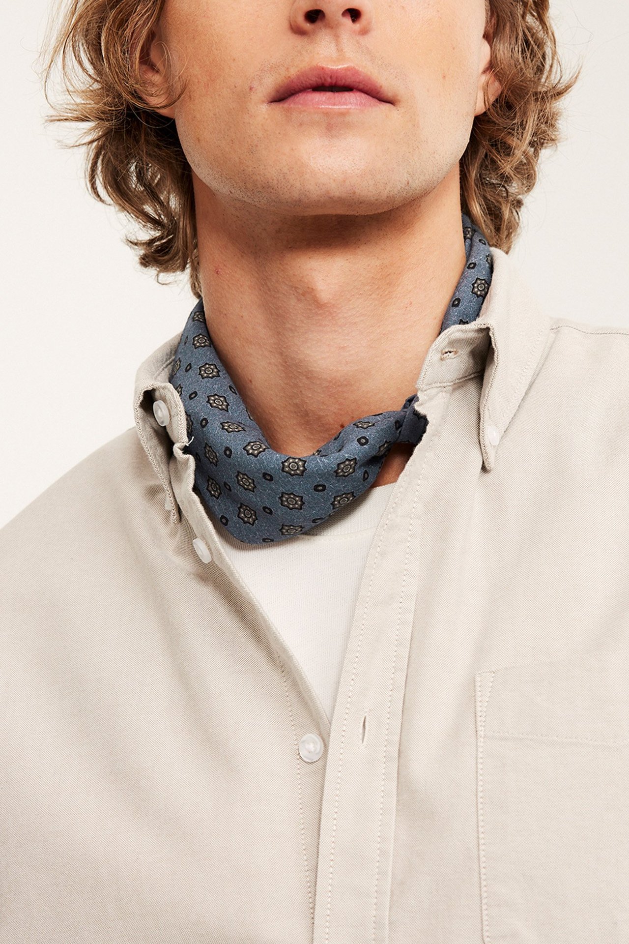 Miesten asusteet, miesten huivit. Mies, joka käyttää huivia beige-paidan ja valkoisen t-paidan kanssa.