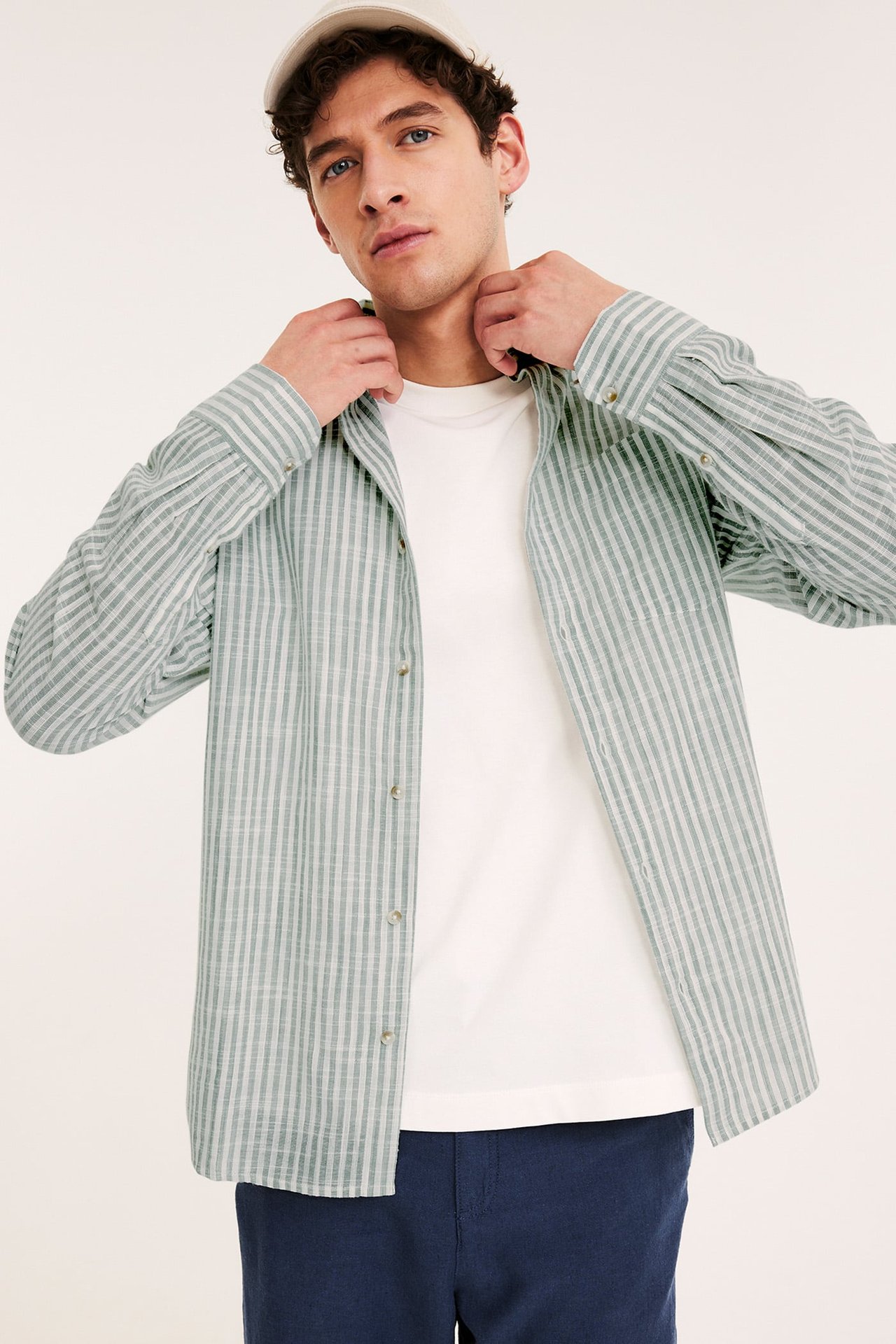 Herrkläder, man med randig bomullsskjorta och blå linnebyxor. Håller i en totebag.