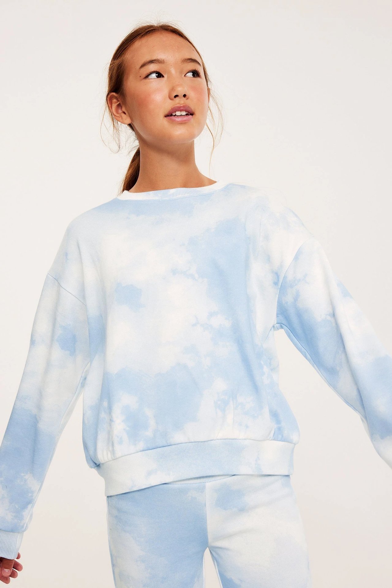 Jente i lyseblått sett, genser og leggings, med skymotiv.