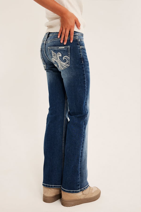Närbild på ett par jeans med broderade bakfickor.