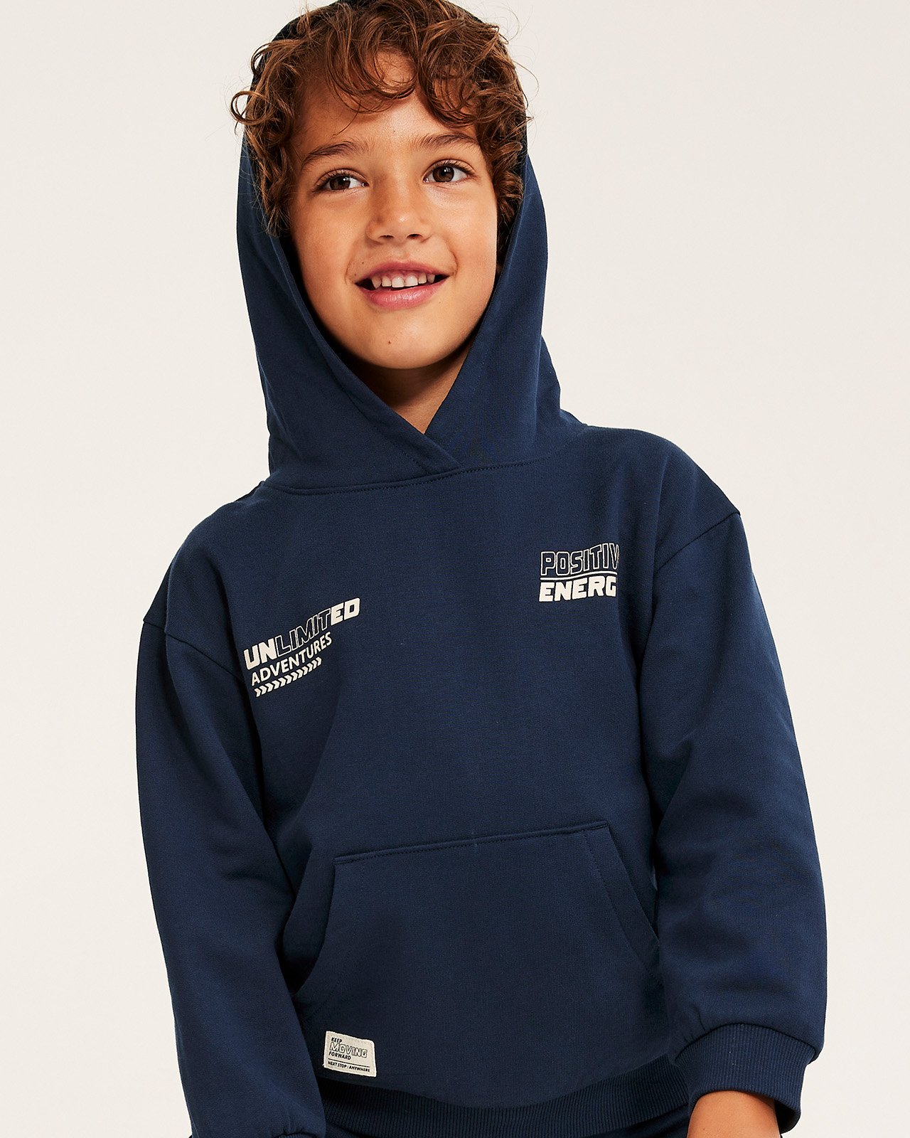 Pojke klädd i mörkblå sweatshirt och mjukisbyxor.