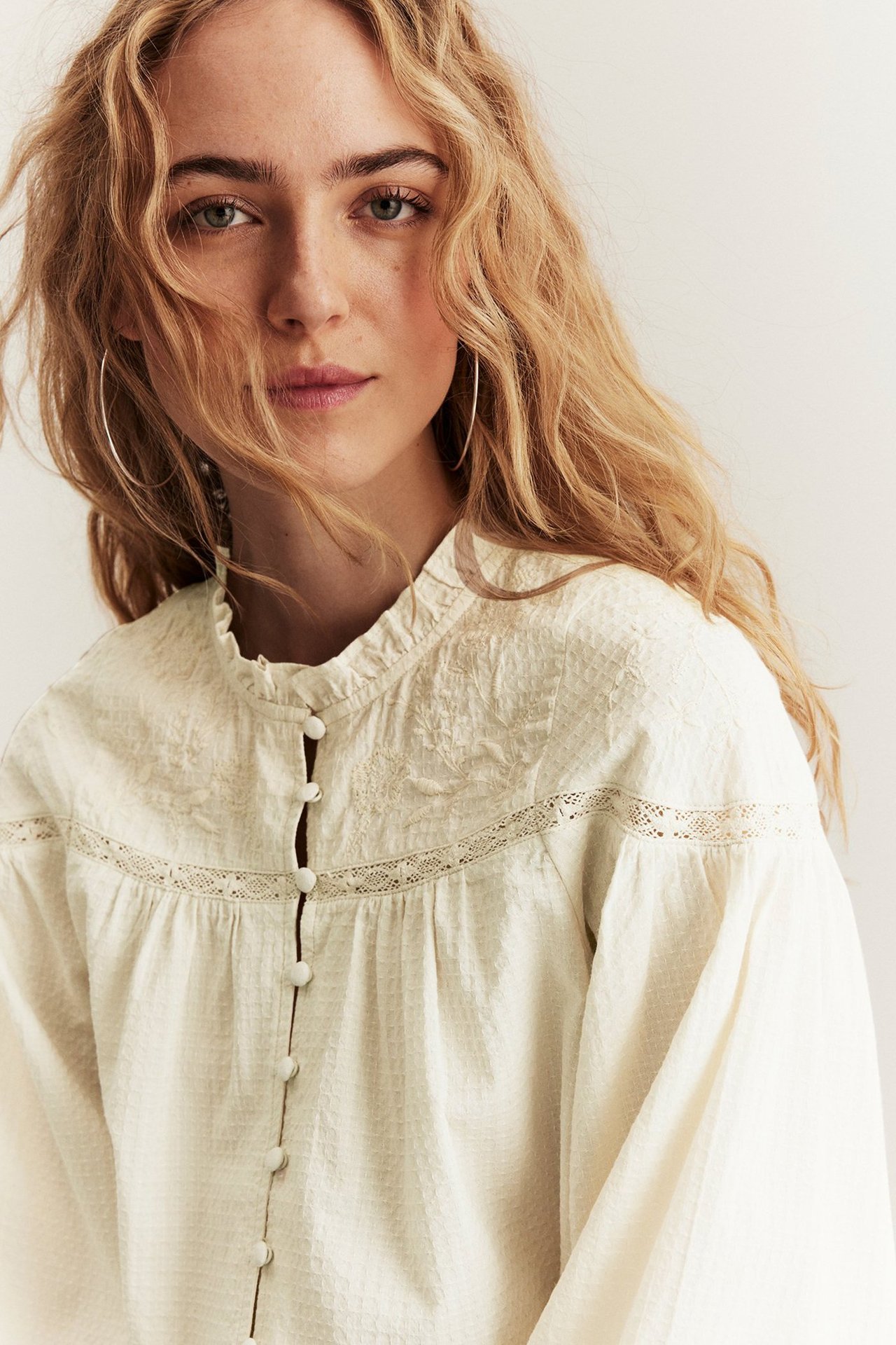 Kvinna klädd i beige blus från Newbie.