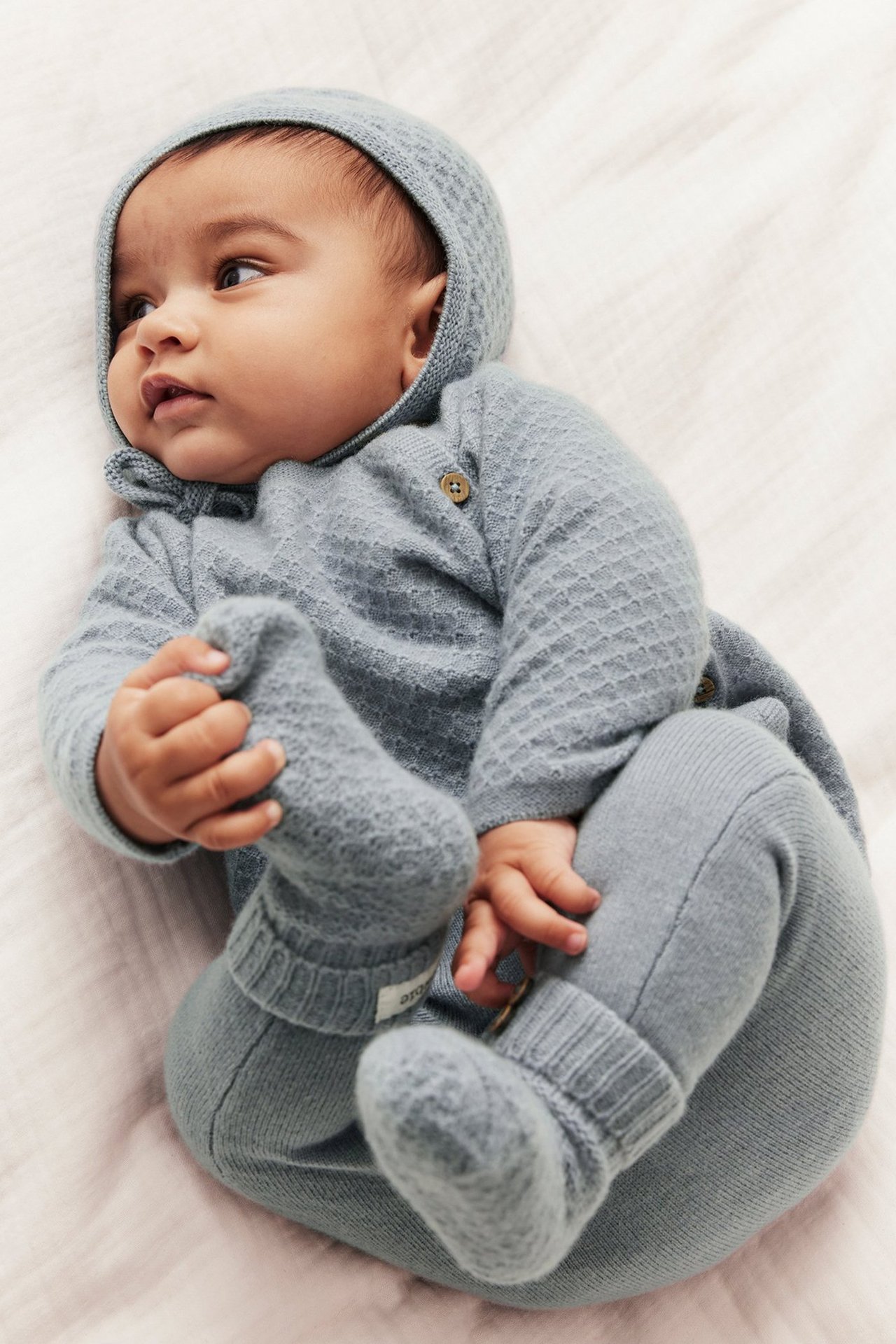 Dziecko leżące w pasujących niebieskich majtkach od Newbie w wełnie.