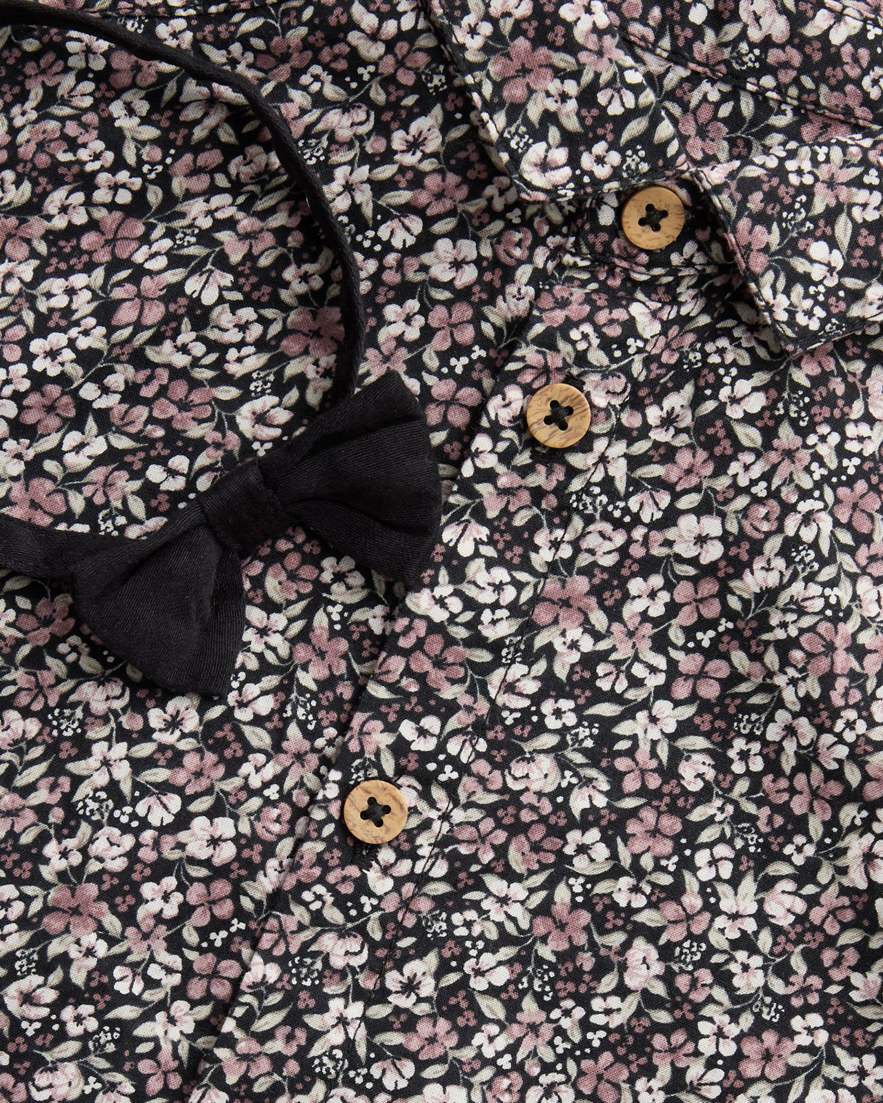 Zbliżenie na zapiętą na guziki koszulę w kwiaty i muszkę.