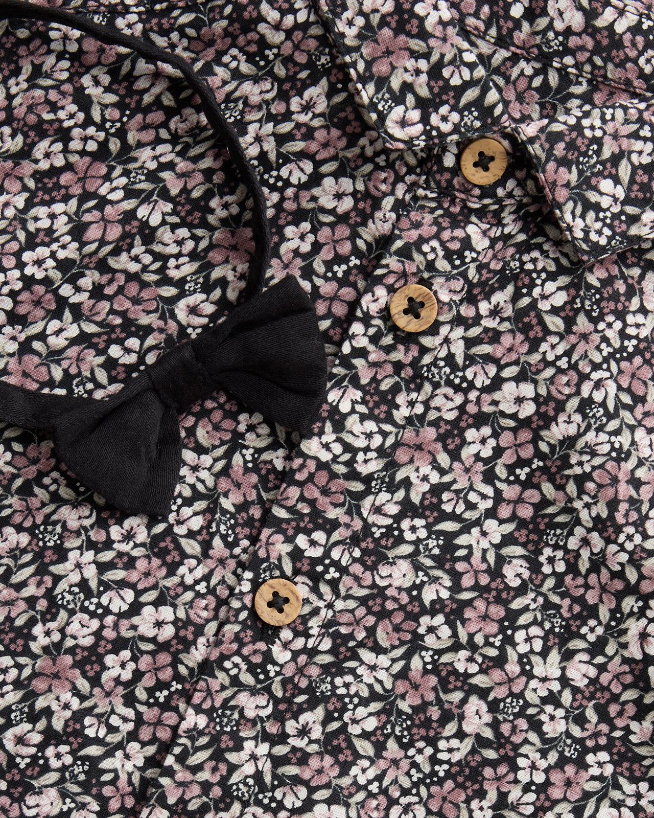 Zbliżenie na zapiętą na guziki koszulę w kwiaty i muszkę.
