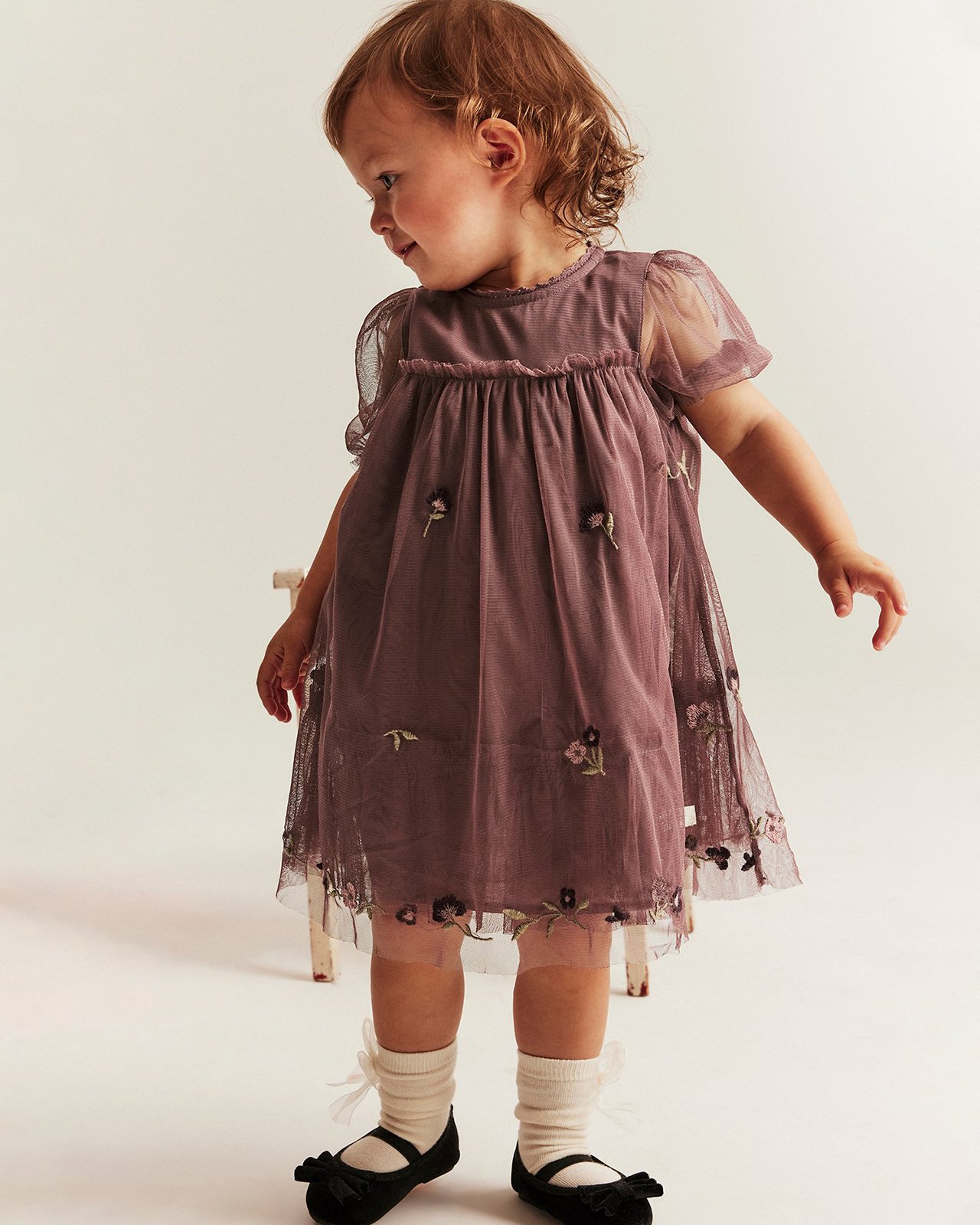 Dziecko ubrane w fioletową siateczkową sukienkę od Newbie.