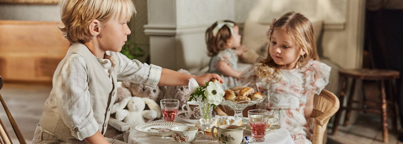 Dzieci, które organizują imprezę i siedzą przy stole i piją kawę.