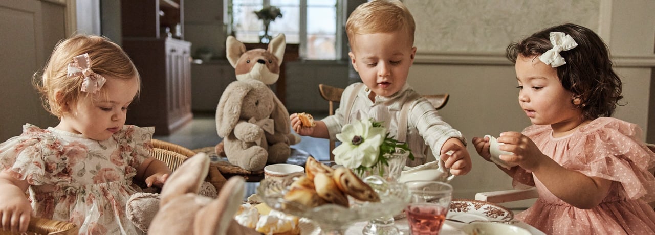 Dzieci, które organizują imprezę i siedzą przy stole i piją kawę.