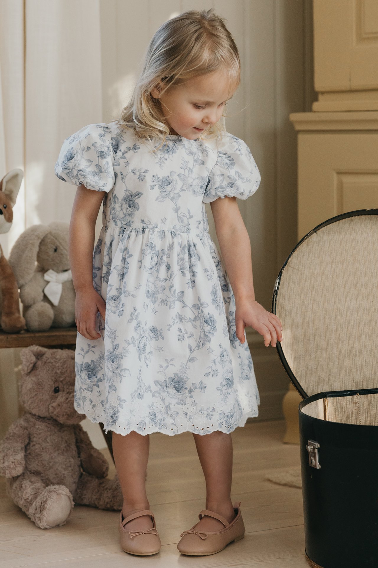 Dzieci ubrane w kwieciste kombinezony od Newbie, stojące na krześle.