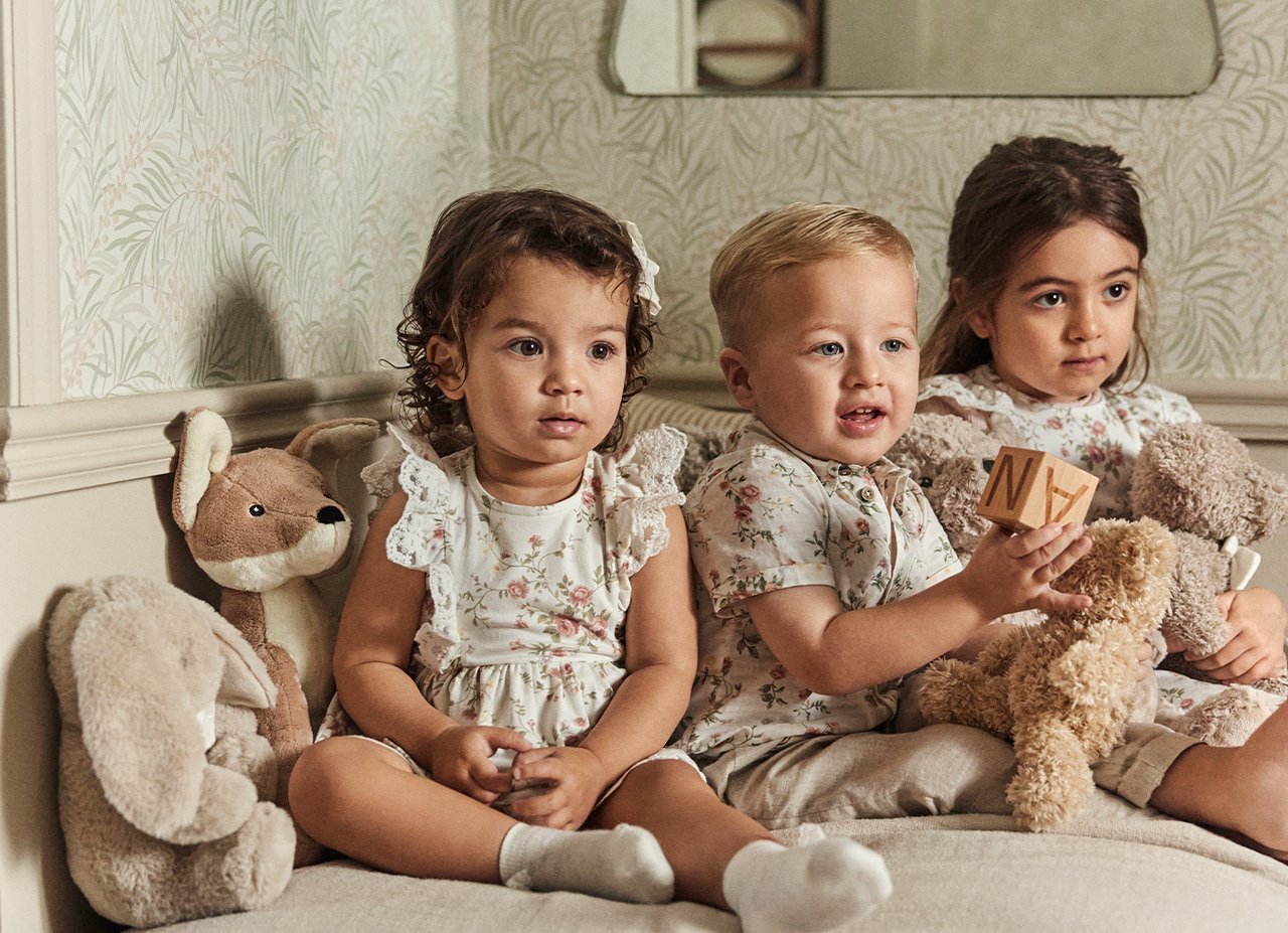 Tre små barn på en sofa i blomstrete klær fra Newbie.