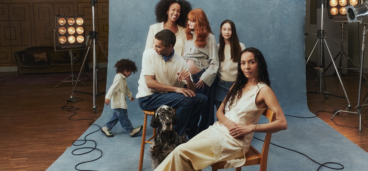 Sex personer, barn och vuxna samt en hund som står framför en backdrop. 