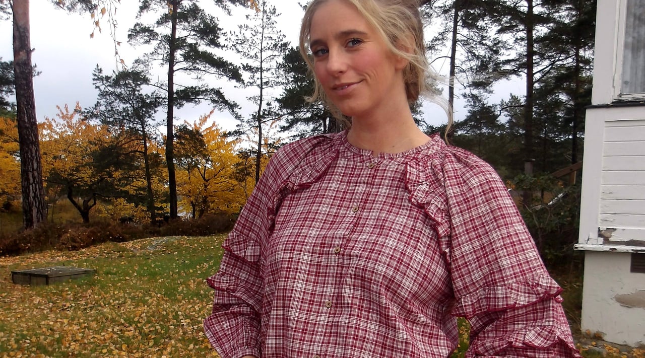 Kvinna utomhus i rutig volangblus.