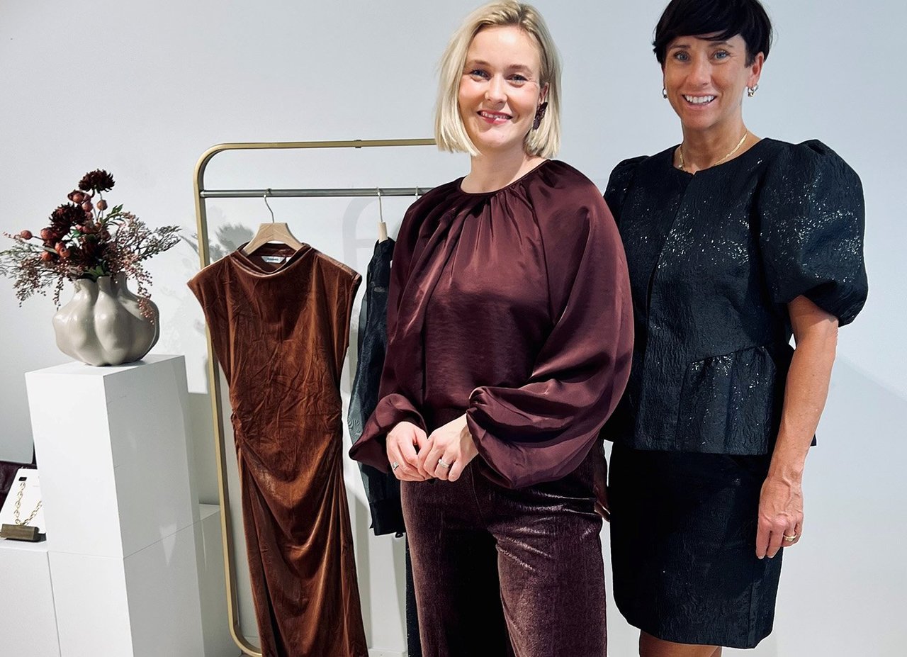 To kvinner i festklær foran et klesstativ.