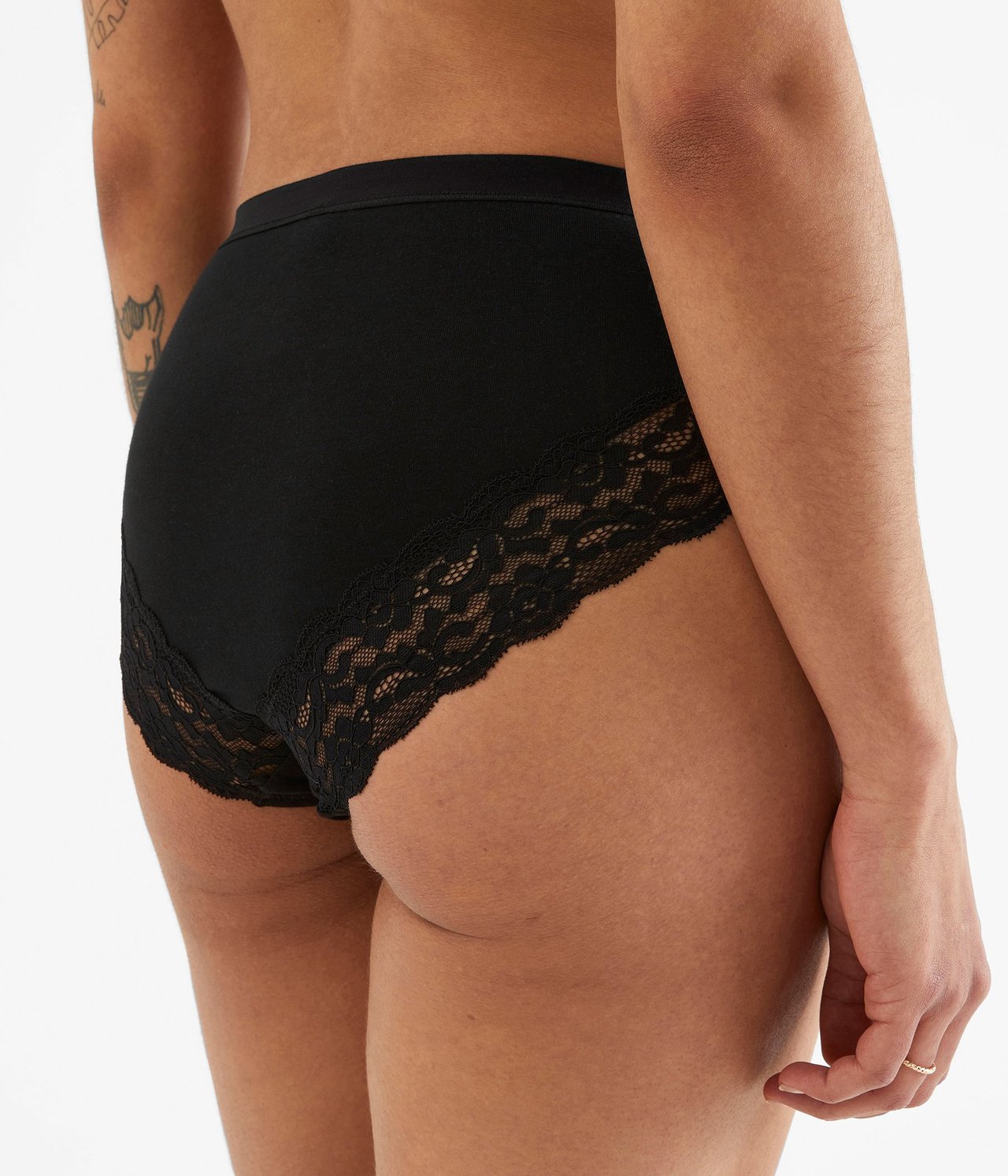 Widok z tyłu kobiety w czarnych bawełnianych figach z delikatną czarną koronką przy wycięciach na nogi.