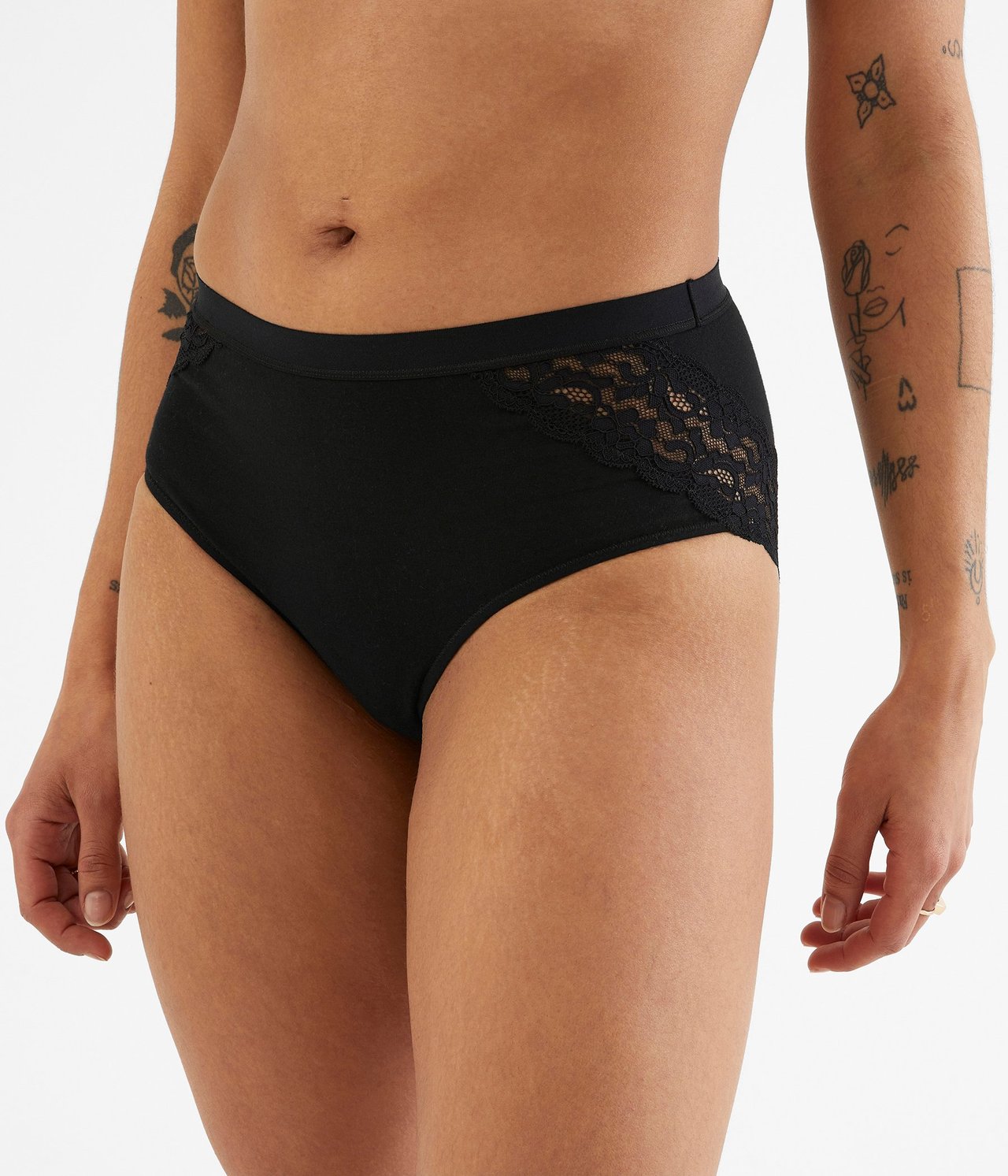 Widok z przodu kobiety w czarnych bawełnianych figach z koronkowymi detalami po bokach.