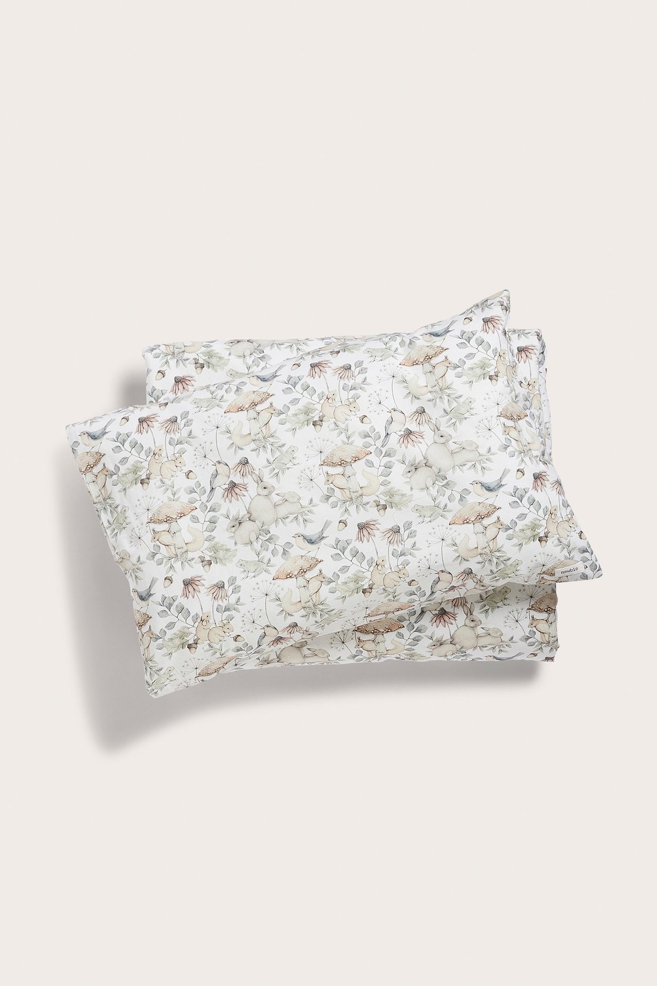 Widok z góry na złożony jasnobeżowy bawełniany komplet pościeli z leśnym wzorem zwierzęcym.