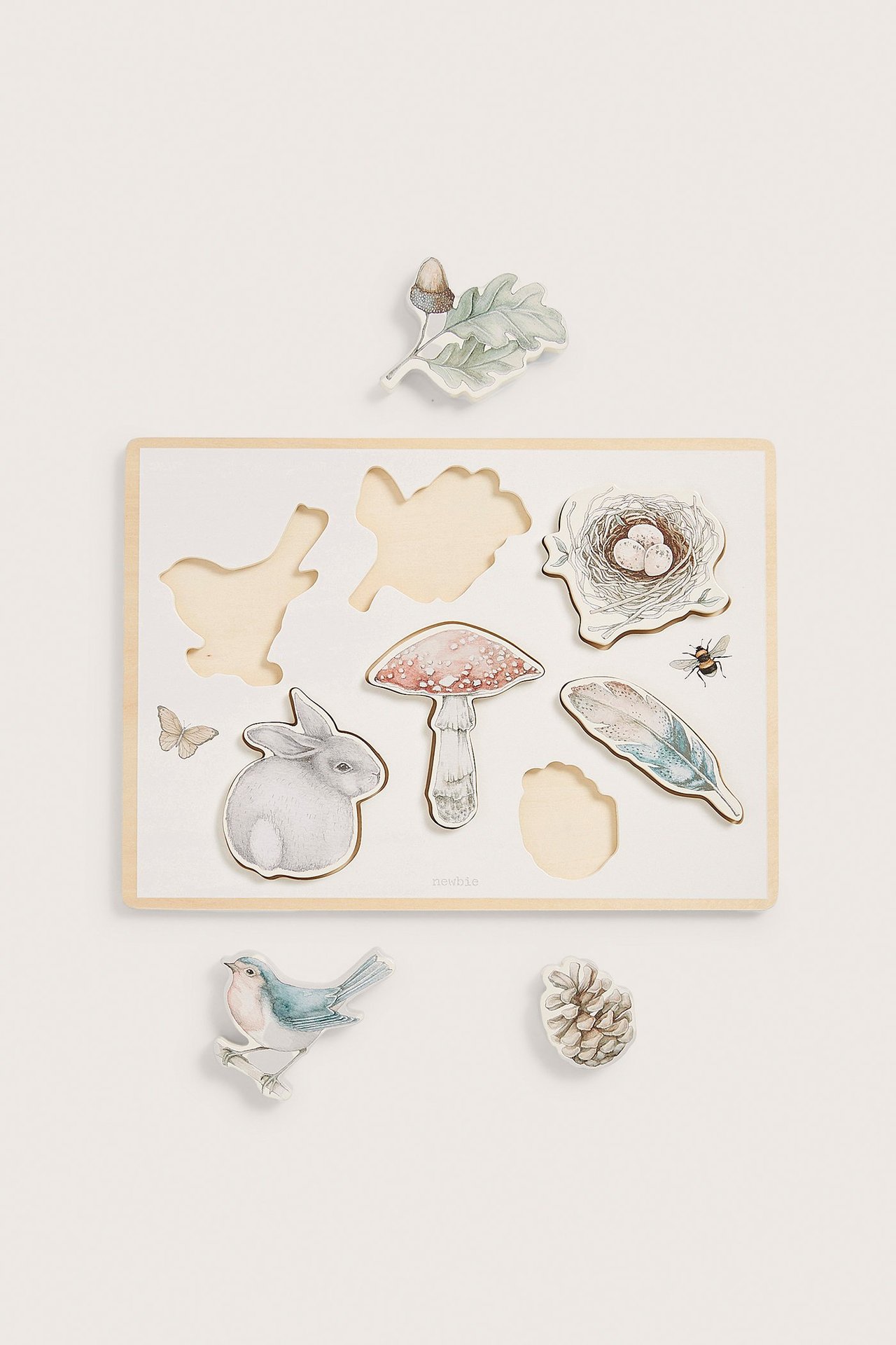 Widok z góry na kremowe drewniane puzzle z motywami leśnych zwierząt i natury, siedem elementów.