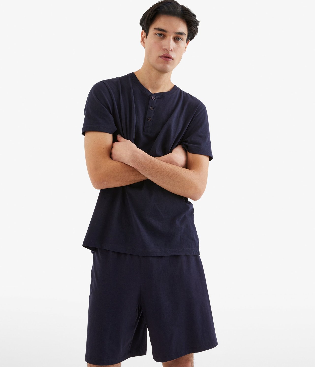 Edestä: Mies tummansinisissä jersey-pyjamashortseissa piilotetulla kuminauhalla ja yhteensopivassa Henley-paidassa.