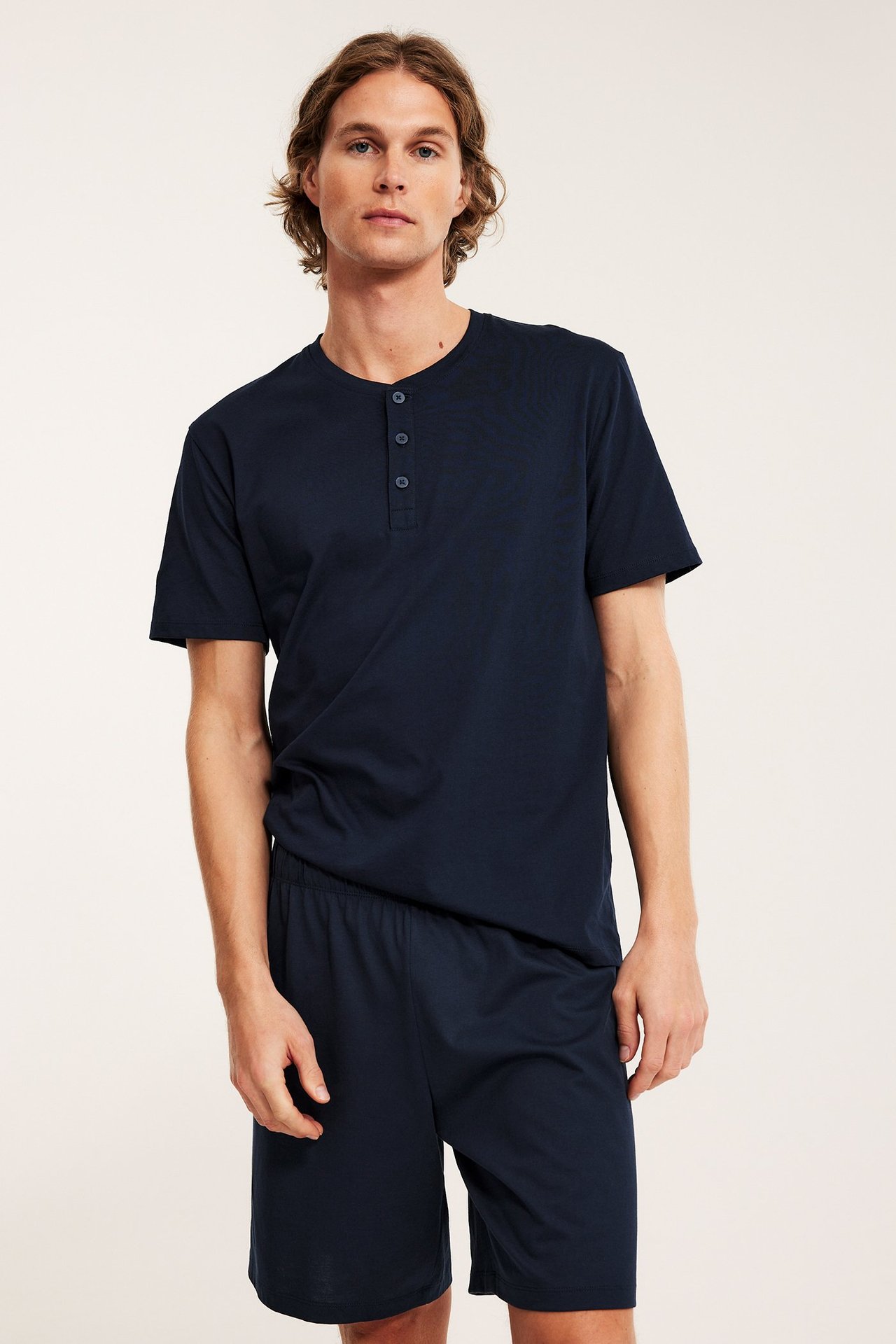 Mies edestäpäin tummansinisissä jersey-pyjamashortseissa ja yhteensopivassa Henley-t-paidassa.