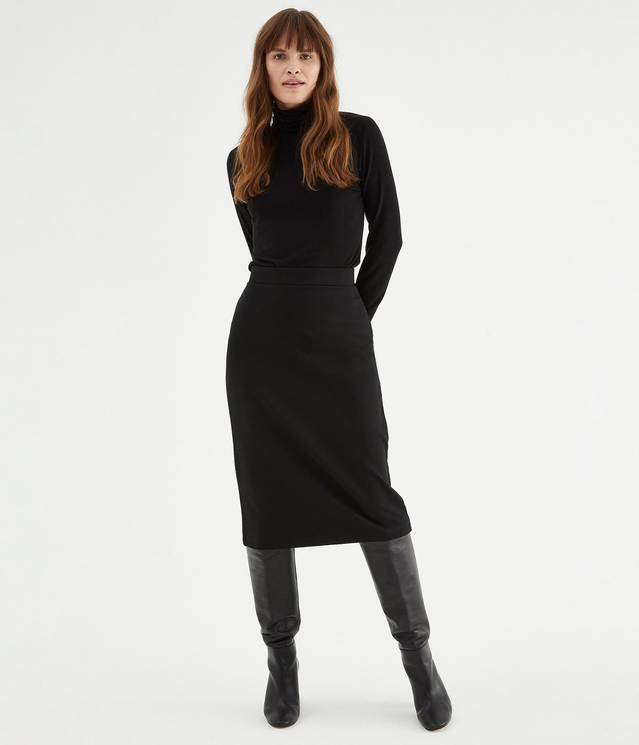 Widok z przodu: Kobieta w czarnej ołówkowej spódnicy ponte roma, czarnym golfie i czarnych kozakach.