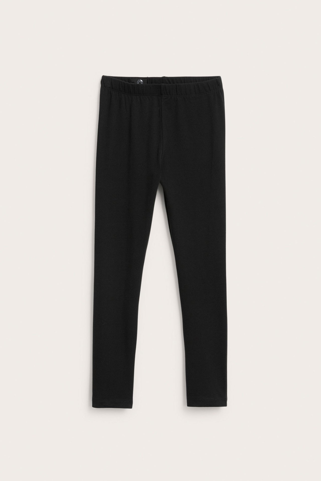 Framifrån, svarta barnleggings i normal passform med resår i midjan.