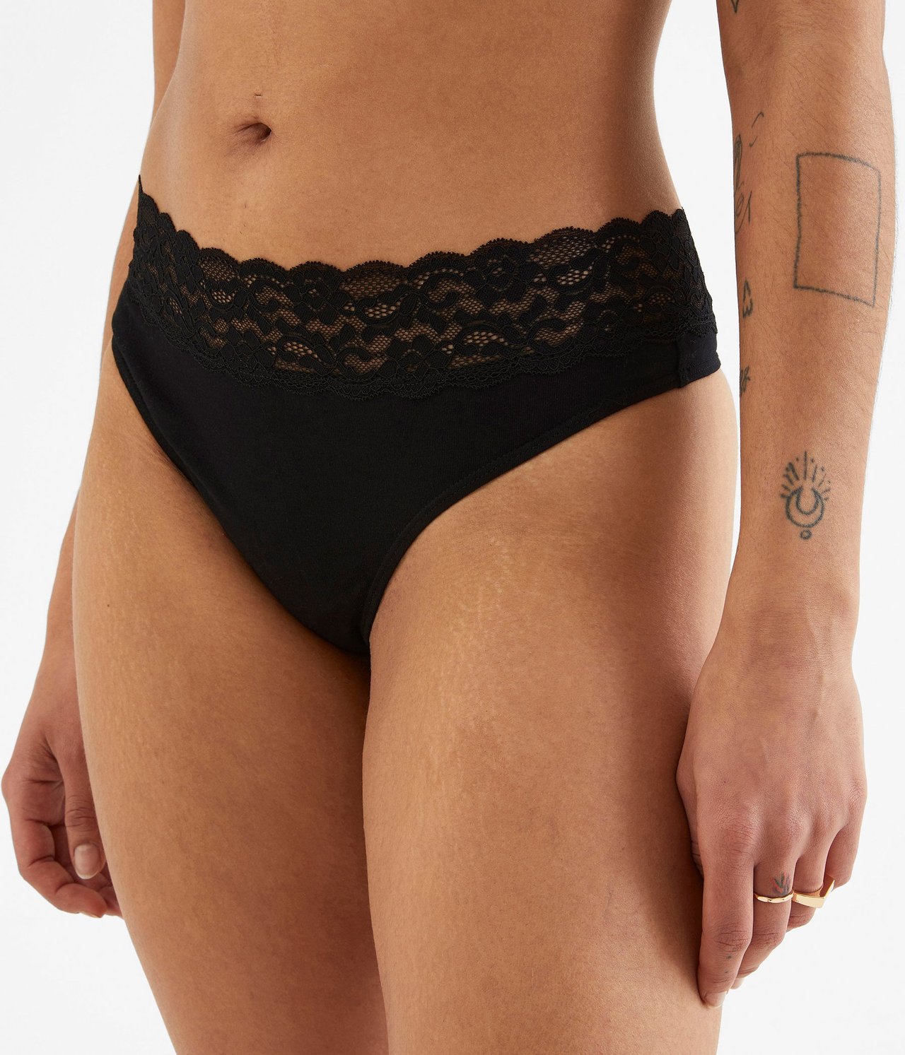 Lähikuva edestä naisesta, yllään mustat puuvillaiset stringit pitsivyötäröllä.