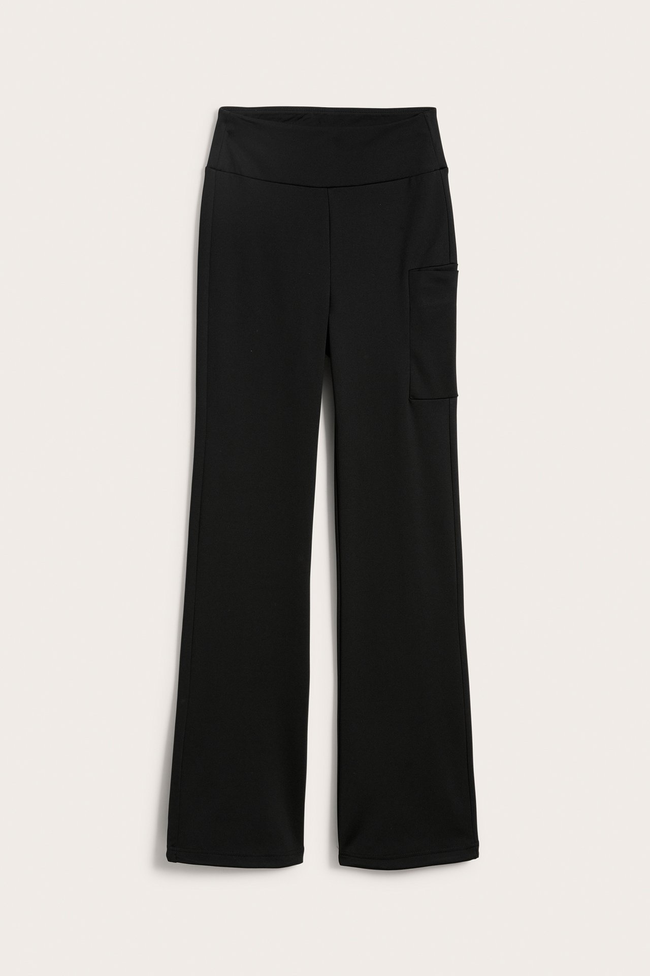 Edestä näkymä mustista korkeavyötäröisistä bootcut-treenitrikoista, joissa sivutasku ja leveät lahkeet.