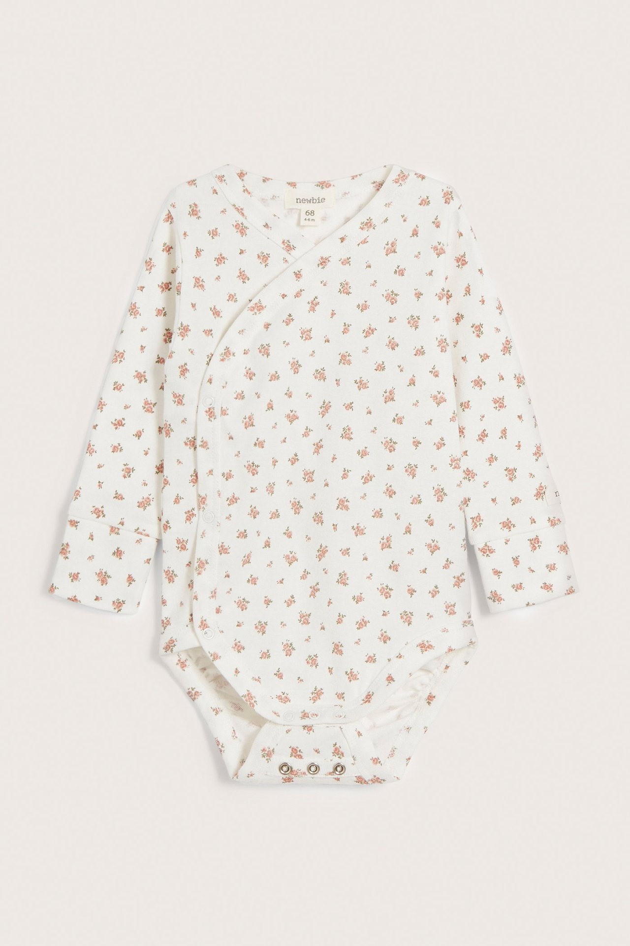Frontvy av en offwhite baby omlottbody i bomull med blommigt mönster och tryckknappar.