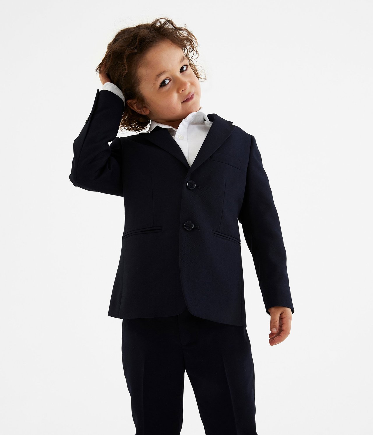 Edestäpäin, lapsi tummansinisessä bleiserissä, valkoisessa paidassa ja yhteensopivissa tummansinisissä housuissa.