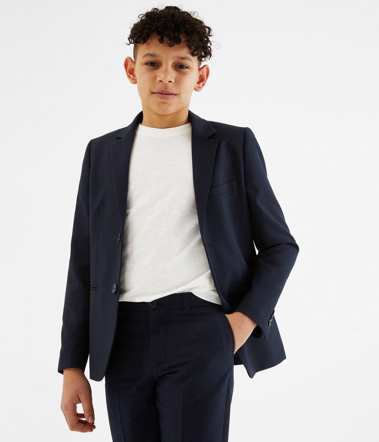 Edestä: Poika yllään tummansininen bleiseri, valkoinen t-paita ja yhteensopivat tummansiniset housut.