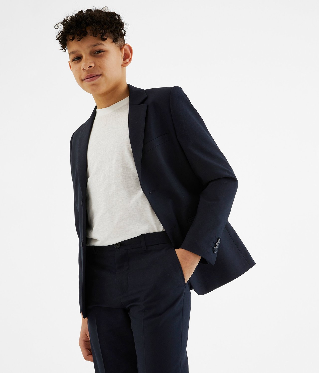 Edestä: Lapsi tummansinisessä bleiserissä valkoisen t-paidan ja yhteensopivien housujen kanssa.